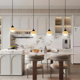 Four marble pendant lights hanging above a kitchen island in a bright white kitchen
