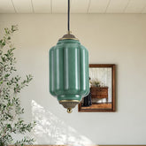 Retro green lantern pendant light with brass accents against a beige wall