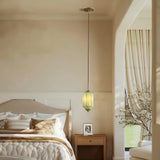 Vintage green pendant light hanging beside a bed with beige decor
