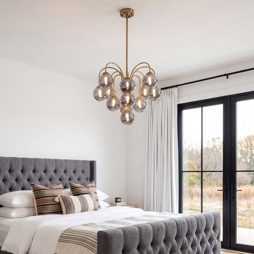 Smoke glass sputnik gold chandelier above tufted grey upholstered master bedroom bed