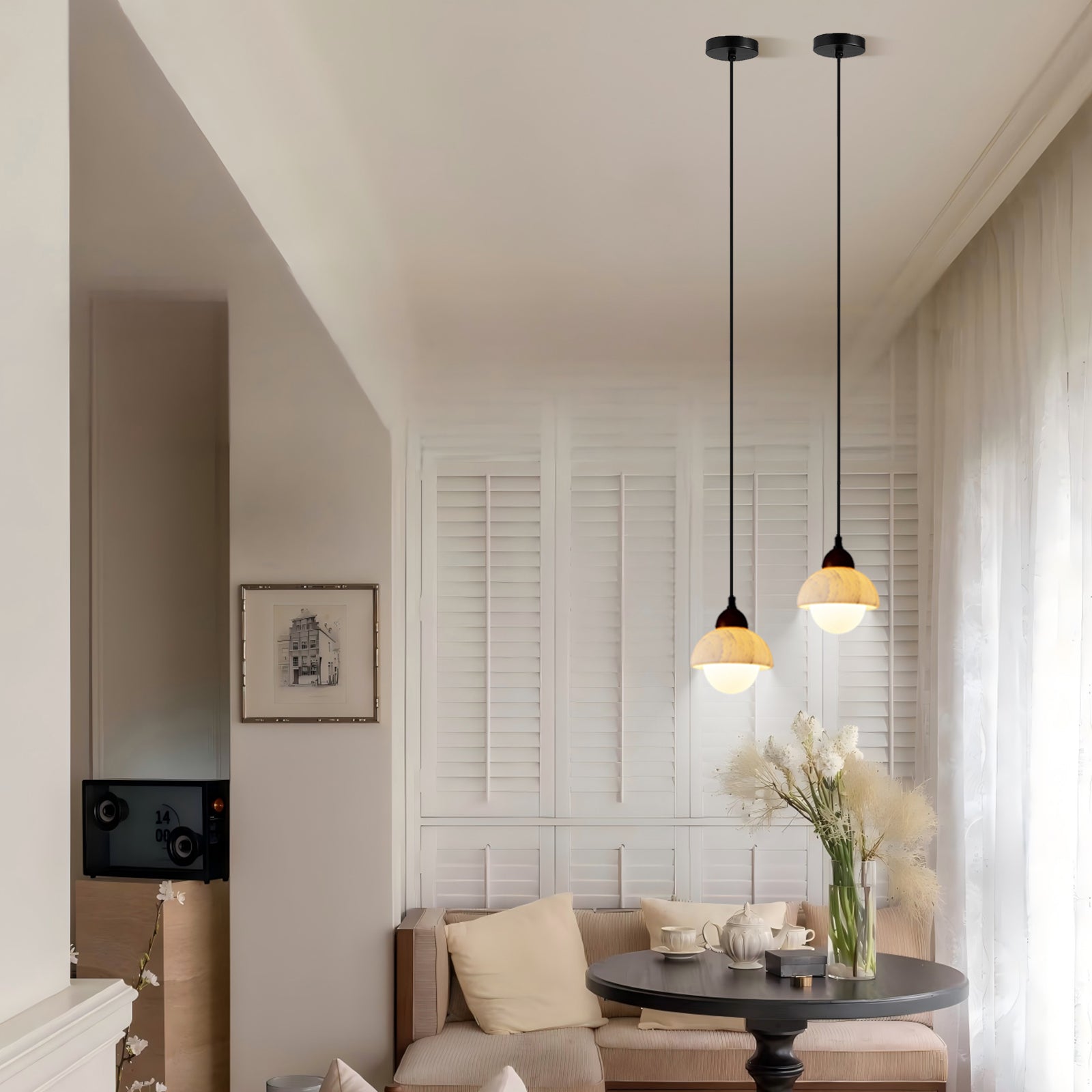 Two marble wood pendant lights hanging in a bright dining room with white shutters