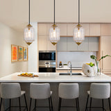 Three vintage clear glass bronze pendant lights above white marble modern kitchen island
